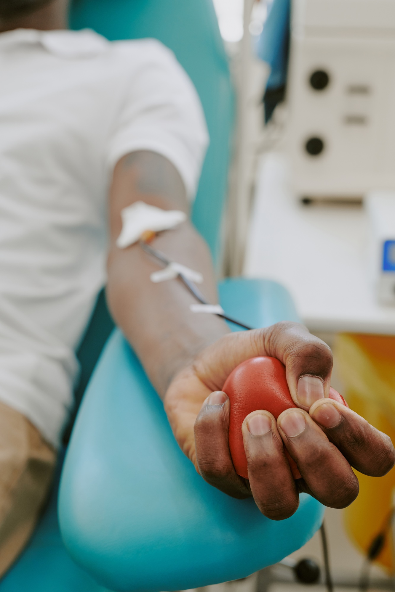 Young Adult Black Man Donating Blood While Squeezing Stress Ball in Clinic
